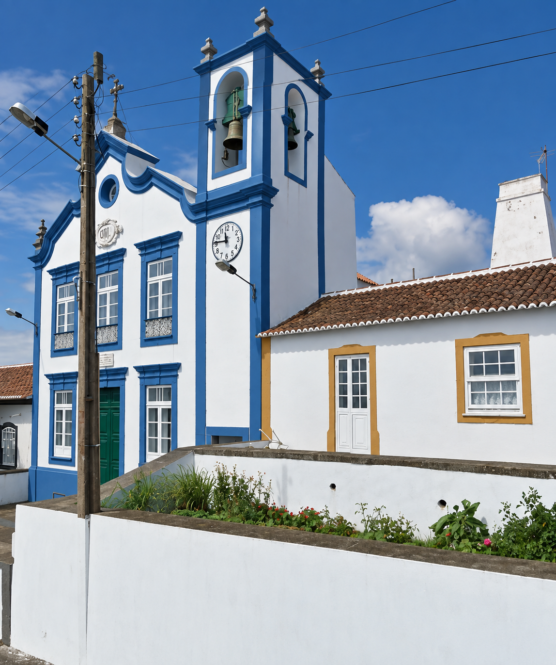 Igreja de Santa Margarida, em Porto Martins, com barras azuis e a casa ao lado